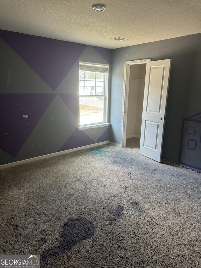 interior space featuring carpet, a closet, visible vents, a textured ceiling, and baseboards