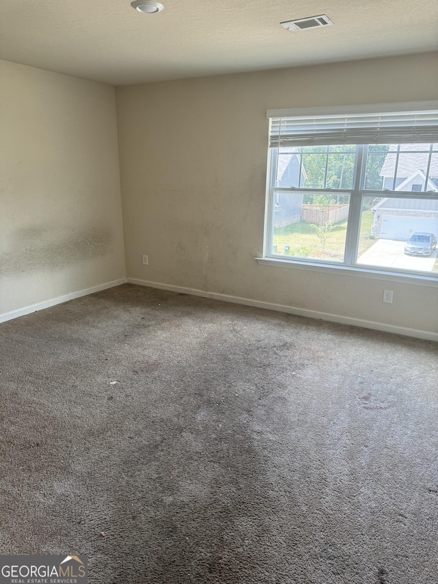 unfurnished room featuring carpet, visible vents, and baseboards