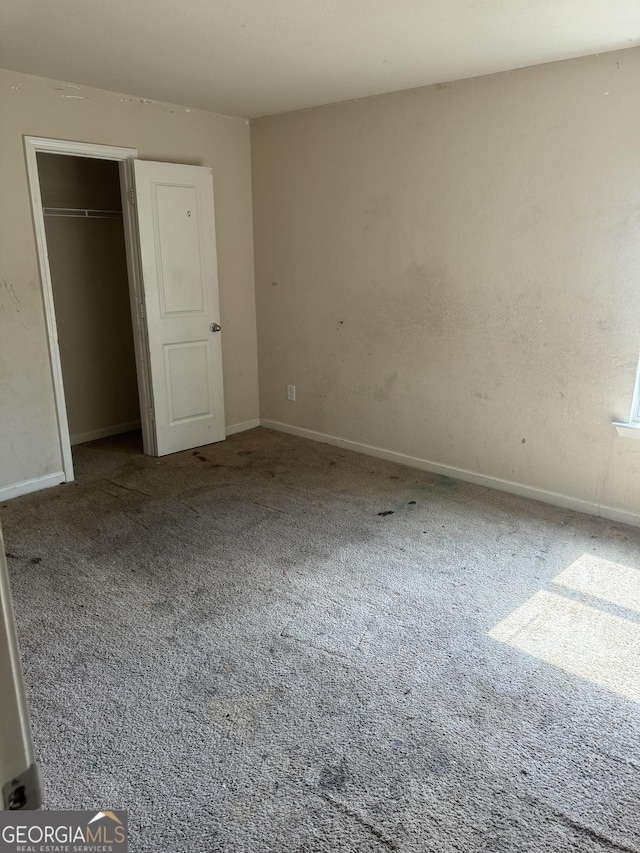 unfurnished bedroom with a closet, carpet flooring, and baseboards