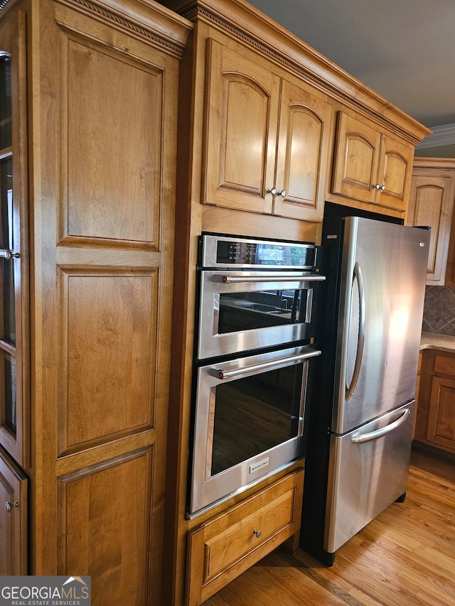 kitchen featuring appliances with stainless steel finishes, crown molding, and light hardwood / wood-style floors