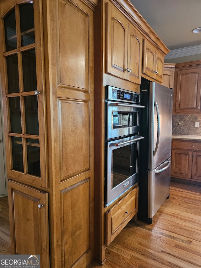 kitchen with light hardwood / wood-style flooring, decorative backsplash, appliances with stainless steel finishes, and ornamental molding