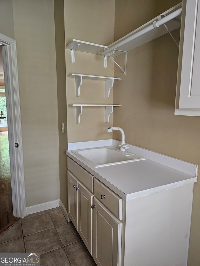 laundry area featuring dark tile patterned flooring and sink