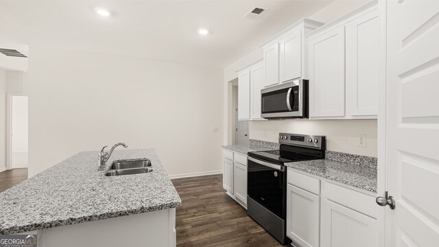 kitchen with dark wood-type flooring, a kitchen island with sink, sink, white cabinetry, and appliances with stainless steel finishes