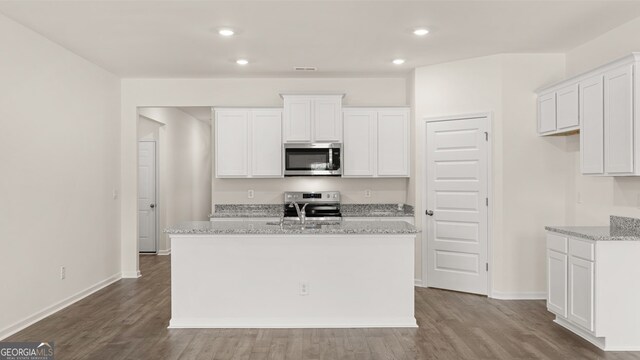 kitchen with stainless steel appliances, white cabinets, and a center island with sink