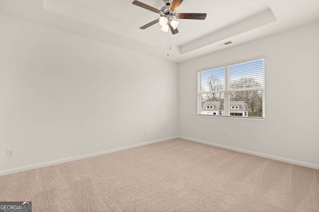 spare room featuring a tray ceiling, ceiling fan, and carpet floors