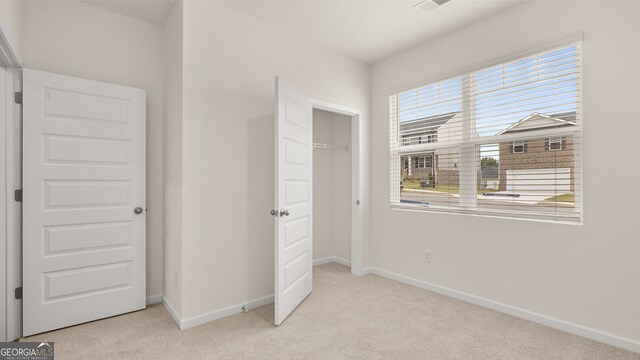 unfurnished bedroom featuring light carpet and a closet