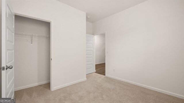 unfurnished bedroom with a closet and light colored carpet