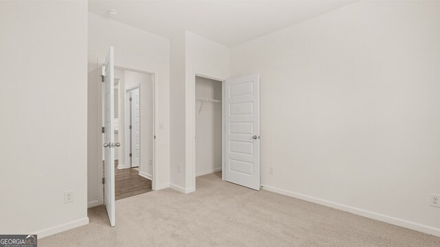 unfurnished bedroom featuring light carpet and a closet