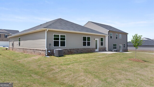 view of front of property with central air condition unit, a front yard, and a patio area