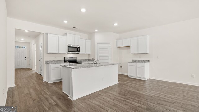 kitchen with stainless steel appliances, white cabinetry, and a center island with sink