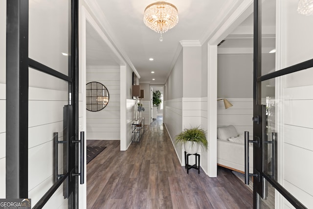 entryway featuring ornamental molding, dark wood-type flooring, and a notable chandelier