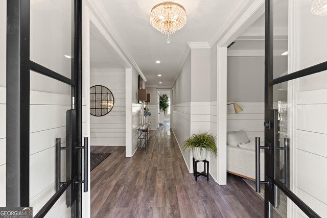 entrance foyer with dark wood-type flooring, a wainscoted wall, ornamental molding, recessed lighting, and a notable chandelier