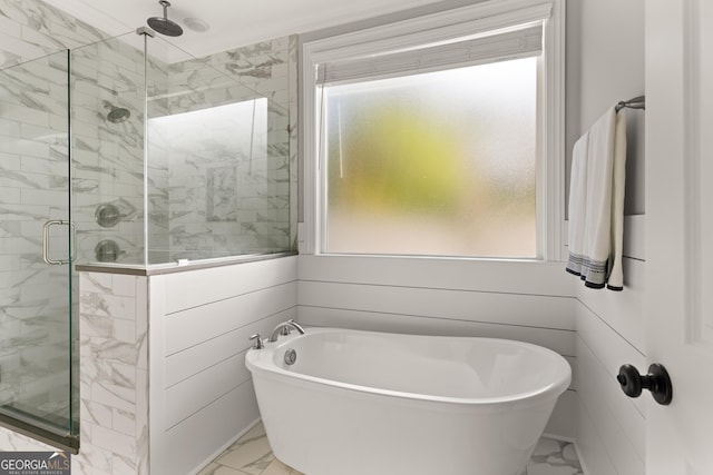 full bath with marble finish floor, a shower stall, and a freestanding tub