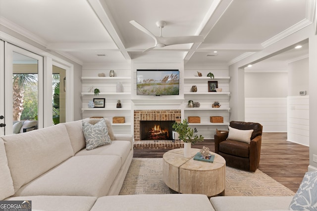 living room with hardwood / wood-style floors, coffered ceiling, a brick fireplace, built in shelves, and beamed ceiling