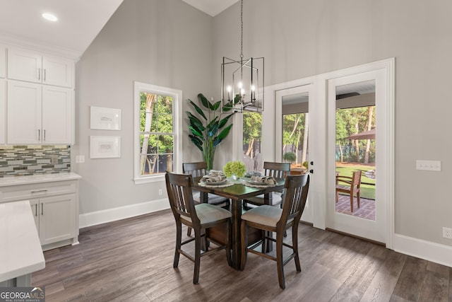 dining room featuring dark wood finished floors, a notable chandelier, high vaulted ceiling, and baseboards