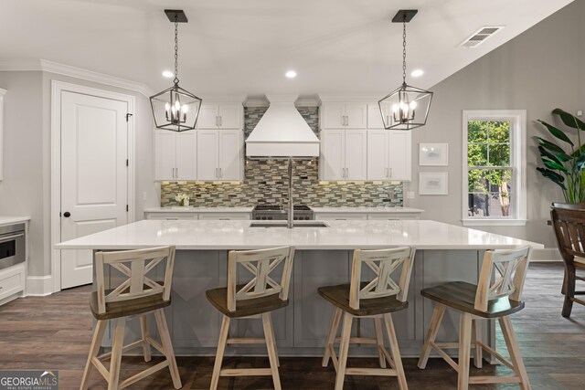 kitchen with custom exhaust hood, visible vents, dark wood finished floors, and tasteful backsplash