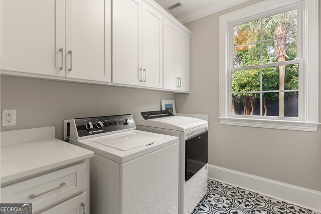 laundry room featuring light tile patterned floors, crown molding, washing machine and dryer, and cabinets