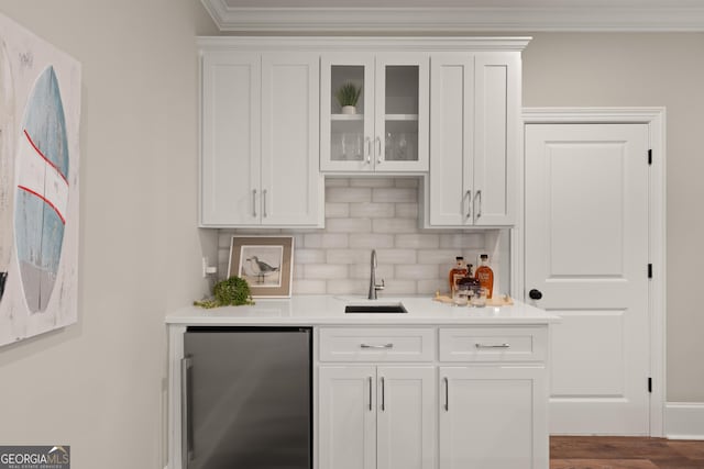 bar featuring tasteful backsplash, stainless steel fridge, sink, and white cabinets