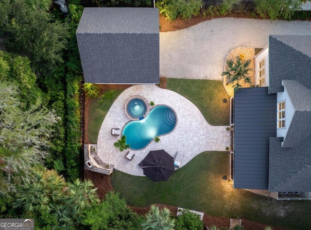 view of swimming pool with a pool with connected hot tub, a patio area, a lawn, a fenced backyard, and exterior fireplace