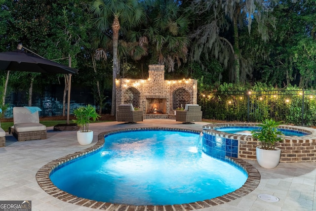 view of pool featuring an outdoor brick fireplace, an in ground hot tub, and a patio