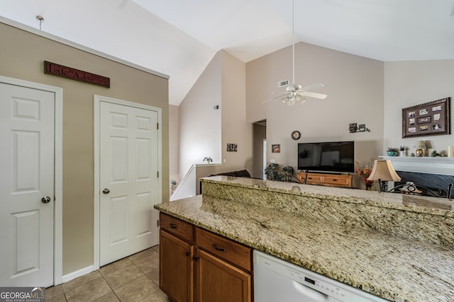 kitchen featuring vaulted ceiling, ceiling fan, light stone counters, and light tile patterned floors