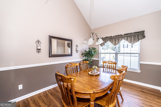 dining space featuring wood-type flooring, a chandelier, and high vaulted ceiling