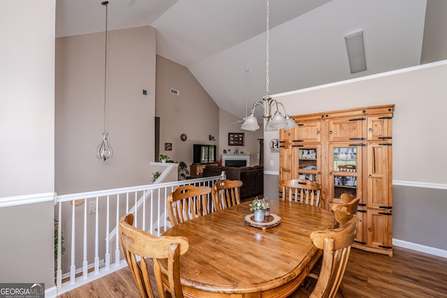 dining area with hardwood / wood-style flooring, a chandelier, and high vaulted ceiling