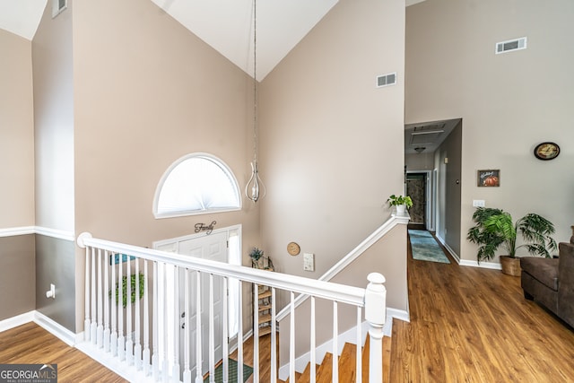 stairs featuring hardwood / wood-style floors and high vaulted ceiling