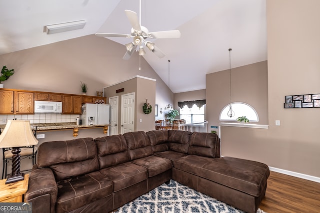 living room with dark hardwood / wood-style floors, ceiling fan, and high vaulted ceiling