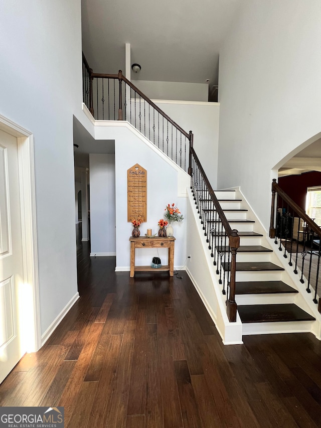 stairway with hardwood / wood-style floors and a high ceiling