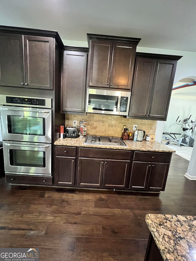 kitchen with dark brown cabinetry, stainless steel appliances, backsplash, and dark hardwood / wood-style flooring