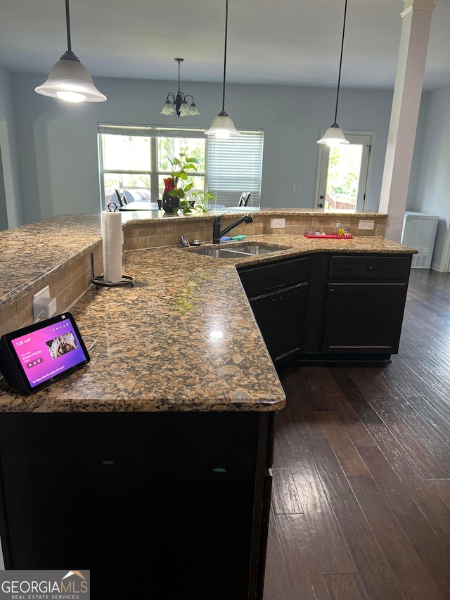 kitchen with dark hardwood / wood-style flooring, a kitchen island with sink, light stone counters, and plenty of natural light