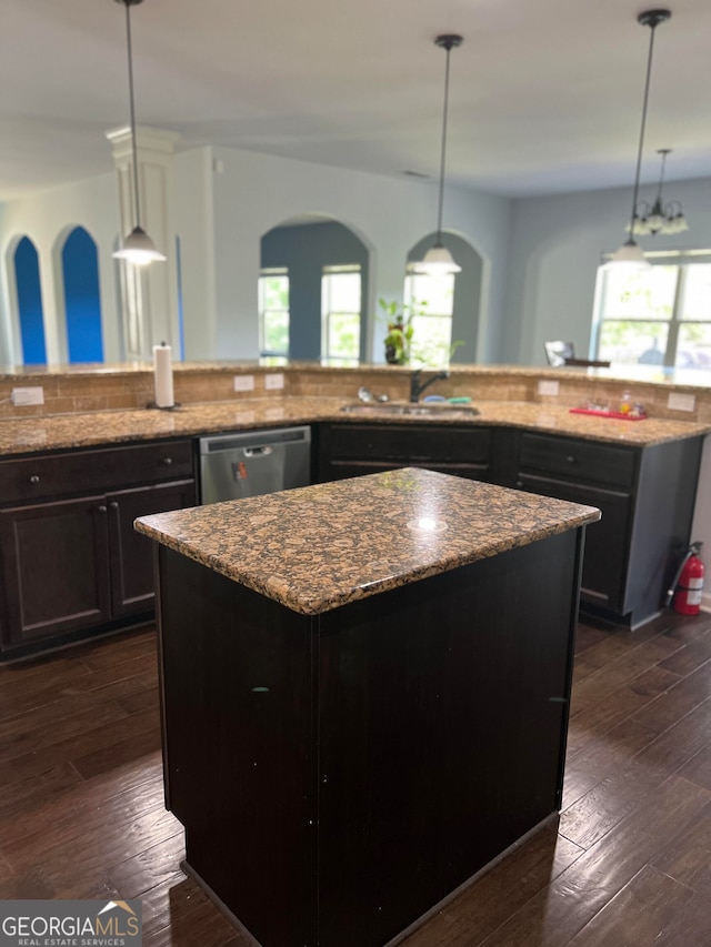 kitchen with light stone countertops, a center island, stainless steel dishwasher, and dark hardwood / wood-style flooring