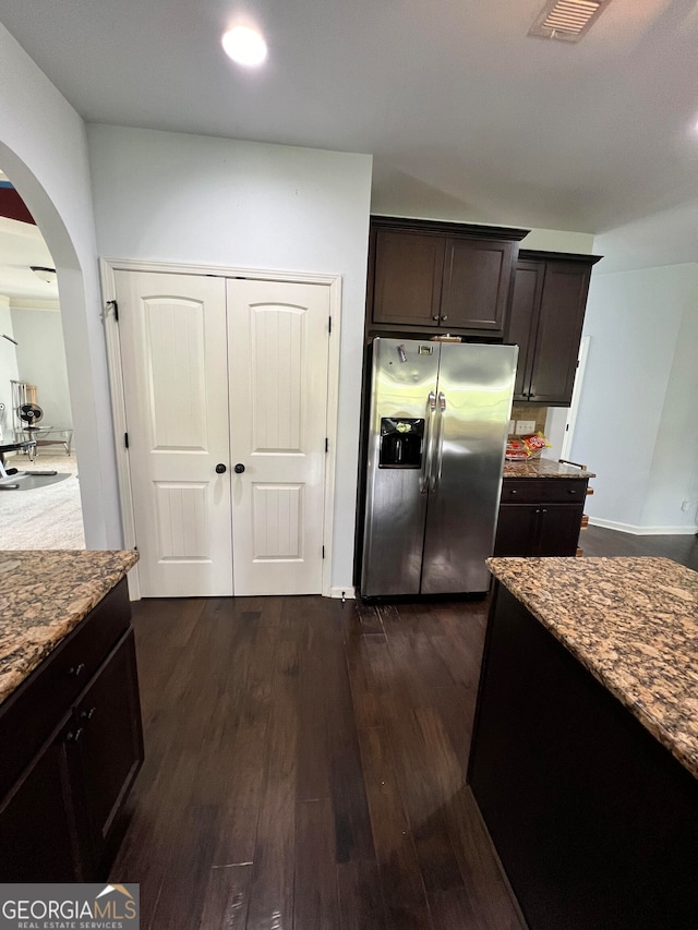 kitchen with stainless steel refrigerator with ice dispenser, stone countertops, dark brown cabinets, and dark hardwood / wood-style floors