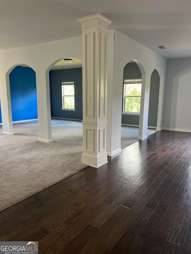 spare room featuring ornate columns and dark hardwood / wood-style floors