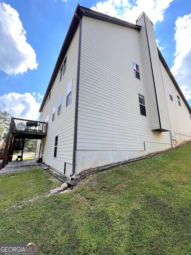 view of side of home featuring a deck and a lawn