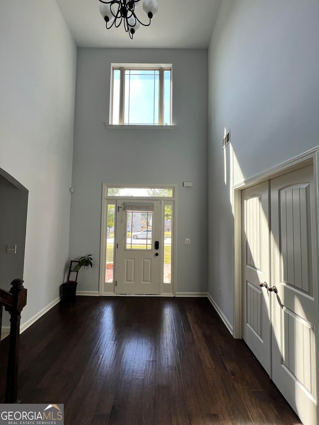 foyer entrance with dark wood-type flooring, a notable chandelier, and a high ceiling