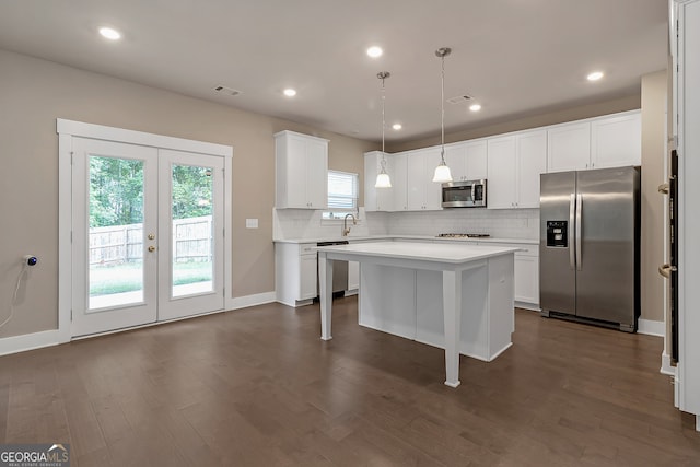 kitchen with dark hardwood / wood-style floors, white cabinetry, hanging light fixtures, a kitchen island, and stainless steel appliances