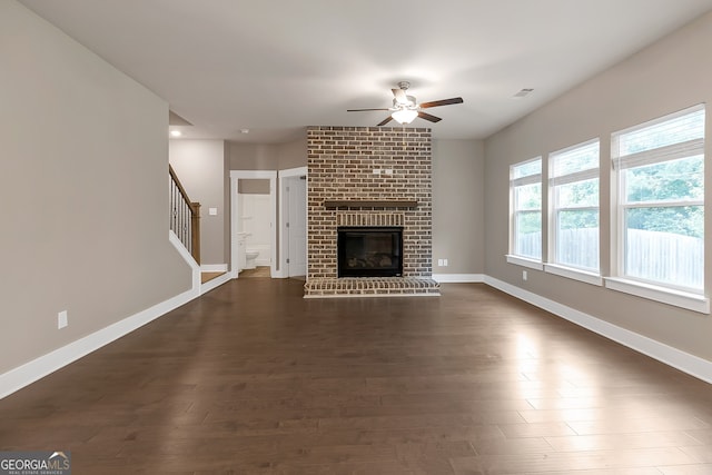 unfurnished living room with a fireplace, dark hardwood / wood-style floors, and ceiling fan