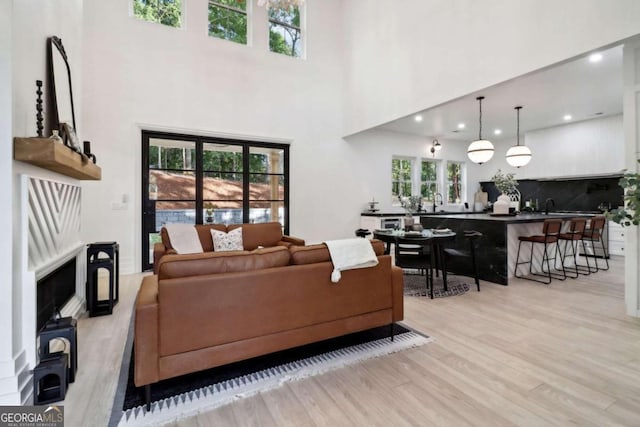 living room featuring a towering ceiling, light hardwood / wood-style floors, and sink