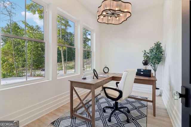 home office with a notable chandelier, light hardwood / wood-style flooring, and a wealth of natural light