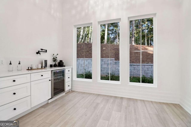 interior space featuring light wood-type flooring, beverage cooler, and white cabinetry