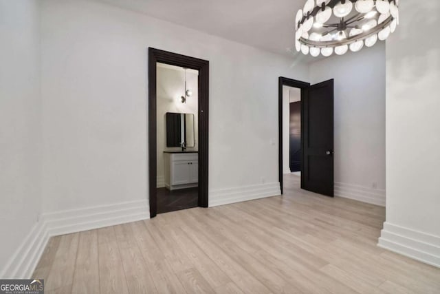 spare room with light hardwood / wood-style floors and a chandelier