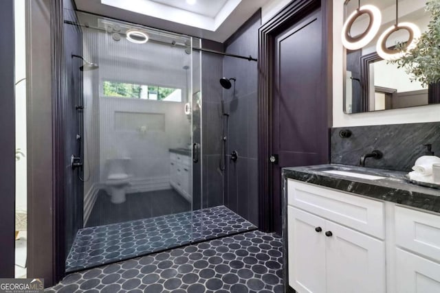 bathroom with tasteful backsplash, a shower with shower door, vanity, and toilet