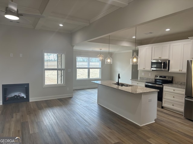 kitchen with light stone countertops, appliances with stainless steel finishes, sink, decorative light fixtures, and white cabinets