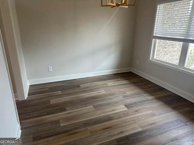 unfurnished dining area with dark hardwood / wood-style floors and an inviting chandelier