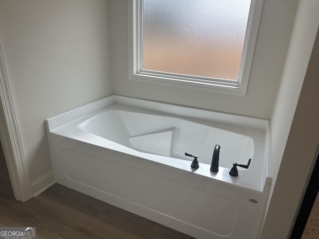 bathroom featuring a tub to relax in and wood-type flooring