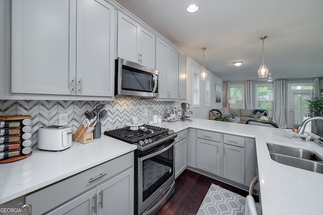 kitchen featuring sink, decorative light fixtures, dark wood-type flooring, stainless steel appliances, and decorative backsplash