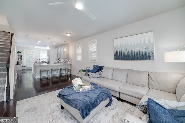 living room featuring ceiling fan and dark wood-type flooring