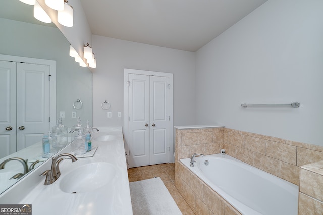 bathroom featuring tile patterned flooring, vanity, and tiled bath